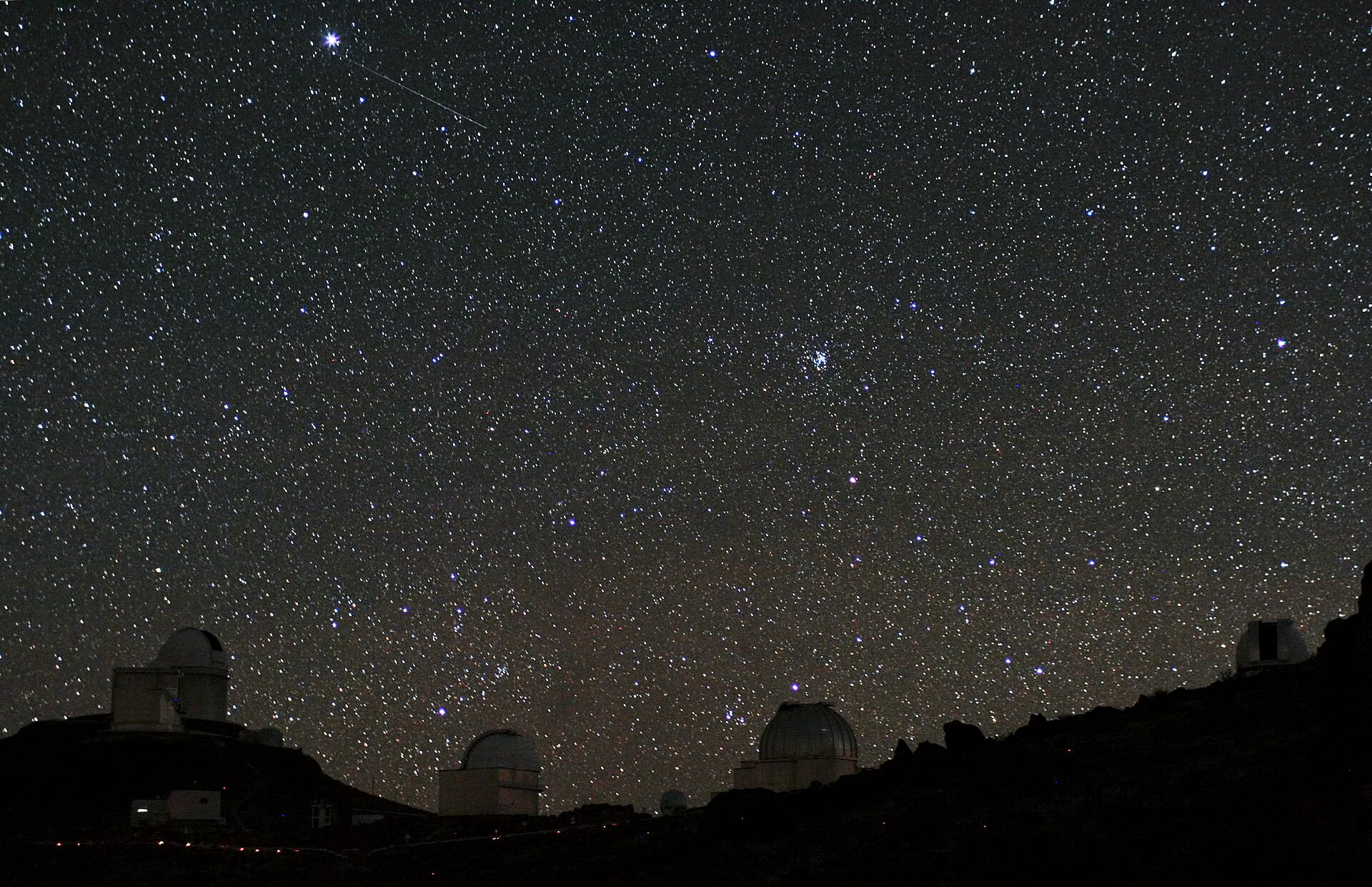 For centuries, philosophers and scientists have wondered about the possibility of habitable planets outside the Solar System. Today, this idea is more than speculation: many hundreds of exoplanets have been discovered over the last couple of decades, by astronomers all over the world. Various different techniques are used in this search for new worlds. In this unusual photograph, telescopes using two of these methods, the ESO 3.6-metre telescope with the HARPS spectrograph, and the space telescope CoRoT, have been captured in the same shot. The photograph was taken by Alexandre Santerne, an astronomer who studies exoplanets himself. The High Accuracy Radial velocity Planetary Search (HARPS) spectrograph, the world’s foremost exoplanet hunter, is an instrument on ESO’s 3.6-metre telescope. The open dome of this telescope can be seen on the left of this image, behind the angular enclosure of the New Technology Telescope. HARPS finds exoplanets by detecting small changes in the motion of a star as it wobbles slightly under the gravitational pull of the orbiting planet. This is known as the radial velocity technique for finding exoplanets. The faint trail of light high in the sky in this 20-second exposure is not a meteor but CoRoT, the Convection Rotation and planetary Transits space telescope. CoRoT searches for planets by looking for the dimming of light from a star which occurs when a planet passes in front of it — the transit method. The space telescope’s location above the Earth’s atmosphere improves the accuracy of its observations by removing the twinkling of stars. Potential planets found by the transit method are confirmed using complementary techniques such as the radial velocity method. Indeed, on very the night that this photograph was taken, HARPS was being used to follow up exoplanet candidates detected by CoRoT! In November 2012, CoRoT unfortunately suffered a computer problem, meaning that — although it is still functioning — it can no longer retrieve data from its telescope (see the news on the CoRoT website , or for example this Nature News article ). The CoRoT team have not given up though, and are working to revive the systems. Whether or not CoRoT can be revived, there is certainly no doubt that the mission has already been a great success! The spacecraft has doubled its originally planned mission lifetime, and was the first spacecraft to discover an exoplanet using the transit method. CoRoT has made great contributions, both to the search for exoplanets, and to the study of the interiors of stars through the field of asteroseismology. The search for exoplanets helps us understand our own planetary system, and may be the first step towards finding life beyond Earth. HARPS and CoRoT are just two of the many exciting instruments developed to assist astronomers with this search. Alexandre submitted this photograph to the Your ESO Pictures Flickr group . The Flickr group is regularly reviewed and the best photos are selected to be featured in our popular Picture of the Week series, or in our gallery. In 2012, as part of ESO’s 50th anniversary year, we are also welcoming your historical ESO-related images. Since submitting the photo, Alexandre has also become an ESO Photo Ambassador .