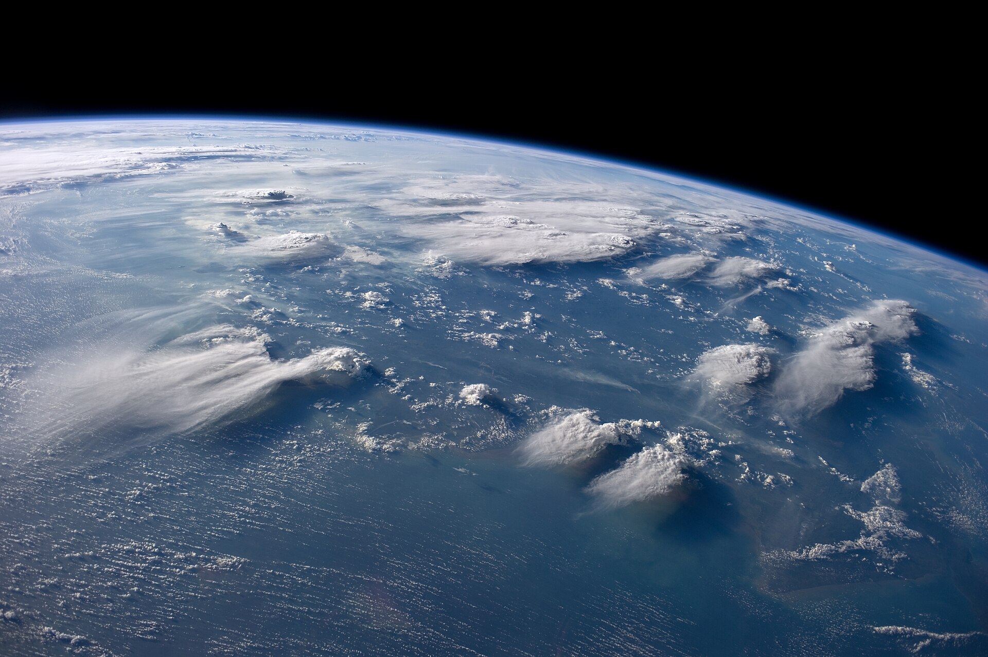 Thunderheads near Borneo , Indonesia are featured in this image photographed by an Expedition 40 crew member on the International Space Station. Crews aboard the International Space Station (ISS) have recently focused their cameras on panoramic views of clouds. Many of the photographs have been taken with lenses similar to the focal length of the human eye. Such images help us see Earth the way ISS crews see it from their perch 350 kilometers above—with a strong three-dimensional sense and a broad view of the planet. In this image, late afternoon sunlight casts long shadows from thunderhead anvils down onto southern Borneo. Near the horizon (image top center), more than 1000 kilometers away from the space station, storm formation is assisted by air currents rising over the central mountains of Borneo. Winds usually blow in different directions at different altitudes. At the time of this photo, high-altitude winds were clearly sweeping the tops off the many tallest thunderclouds, generating long anvils of diffuse cirrus plumes that trail south. At lower levels of the atmosphere, “streets” of white dots—fair-weather cumulus clouds—are aligned with west-moving winds. Small smoke plumes from forest fires in Borneo are also aligned west. Caption by M. Justin Wilkinson, Jacobs and Michael Trenchard, Barrios Technology at NASA-JSC
